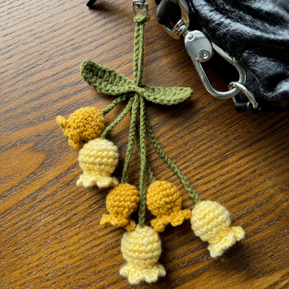 Crocheted yellow and green flower keychain on a wooden surface