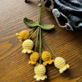Crocheted yellow and green flower keychain on a wooden surface
